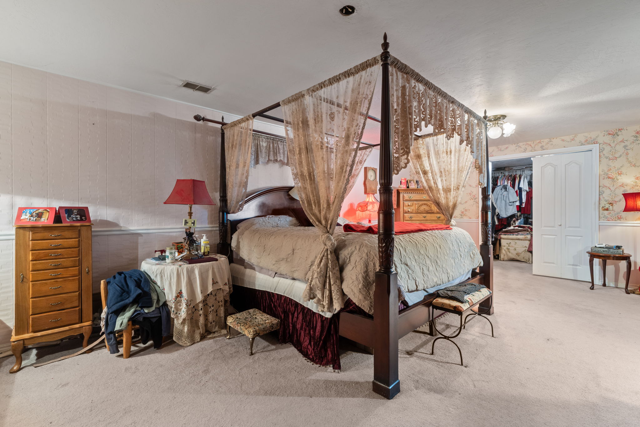 Bedroom featuring wallpapered walls, light carpet, and a closet