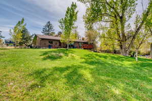 Back of house with brick siding, a yard, and a wooden deck