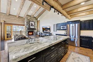 Kitchen with open floor plan, stainless steel appliances, a fireplace, light wood-style floors, and a center island