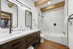 Bathroom featuring double vanity, dark wood-style flooring, bathtub / shower combination, and beamed ceiling
