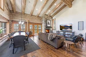 Living area featuring hardwood / wood-style floors, a stone fireplace, a chandelier, and vaulted ceiling