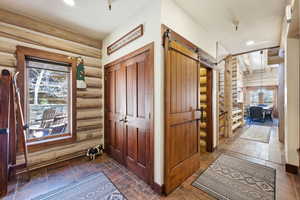 Foyer entrance with a barn door, log walls, and suspended lighting