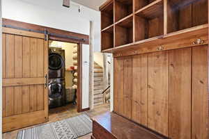 Walk in closet with a barn door, stacked washer and dryer, and tile patterned flooring