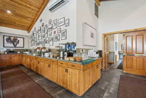 Kitchen with a vaulted wood ceiling, wood finish cabinets, light stone counters, and recessed lighting