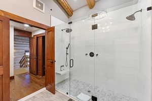 Bathroom featuring a shower stall, log walls, and beamed ceiling