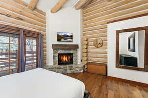 Bedroom featuring dark wood-type flooring, log walls, and a fireplace