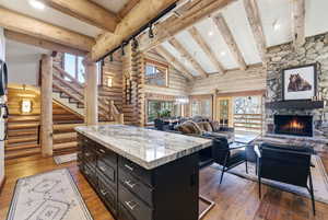 Kitchen with open floor plan, dark cabinetry, dark wood-type flooring, a center island, and a fireplace
