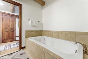 Bathroom featuring a garden tub and beam ceiling