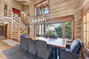 Dining space featuring log walls, hardwood / wood-style flooring, a high ceiling, and suspended lighting