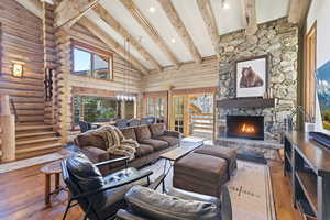 Living area featuring wood-type flooring, a fireplace, rustic walls, lofted ceiling, and recessed lighting