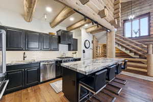 Kitchen featuring log walls, dark cabinets, a kitchen breakfast bar, light wood-style floors, and a kitchen island