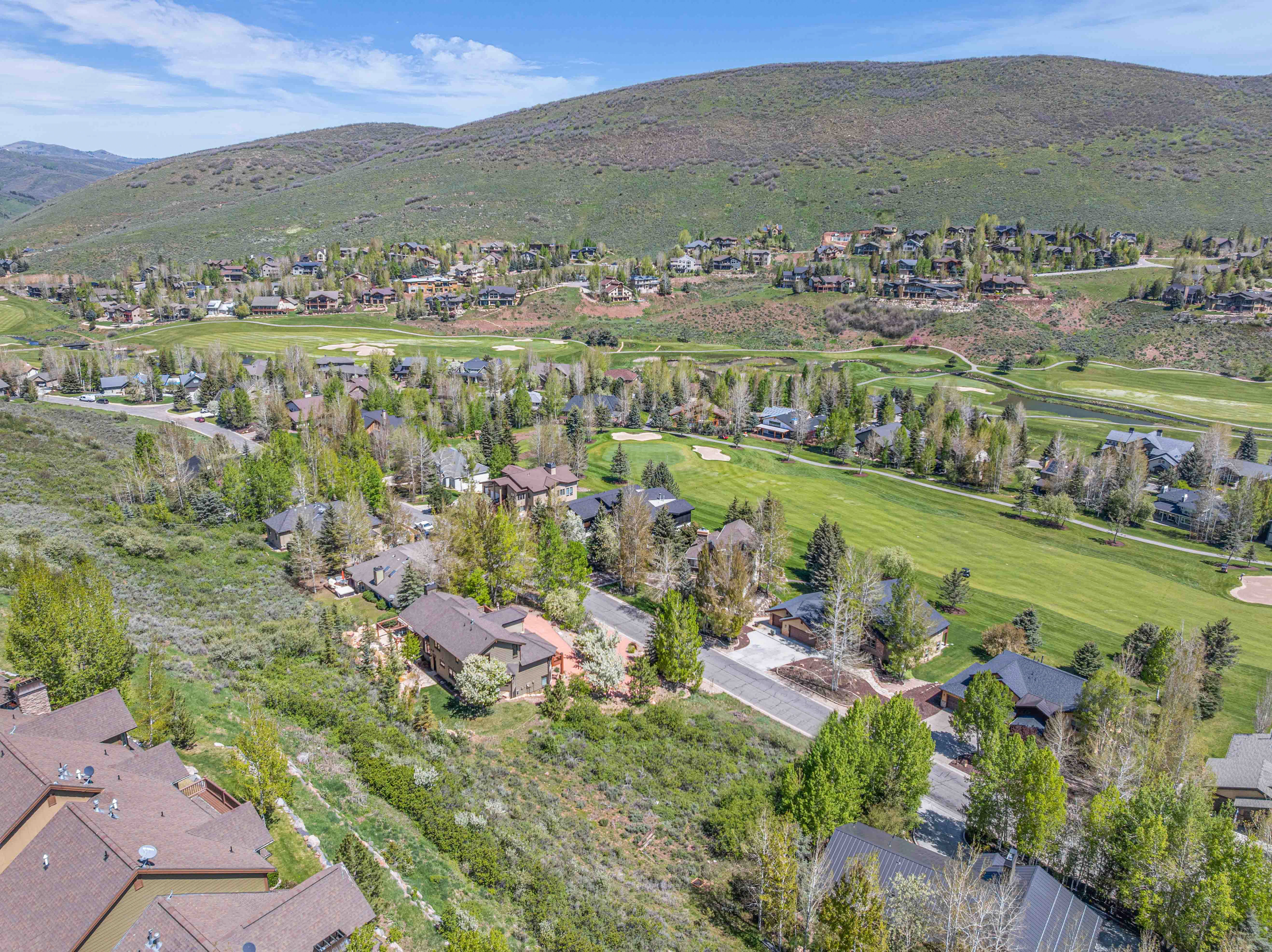 Aerial perspective of suburban area featuring a mountain backdrop and a golf course