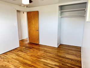 Unfurnished bedroom with hardwood / wood-style flooring, a closet, and a ceiling fan