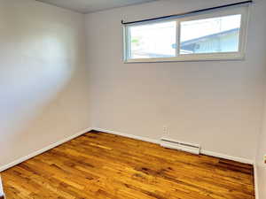 Unfurnished room with hardwood / wood-style floors and a baseboard radiator