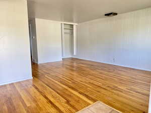 Unfurnished bedroom with light wood-type flooring, a closet, and wood walls