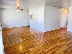Spare room featuring hardwood / wood-style flooring, a ceiling fan, and baseboard heating