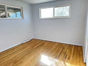 Unfurnished room with light wood-type flooring, healthy amount of natural light, and baseboard heating