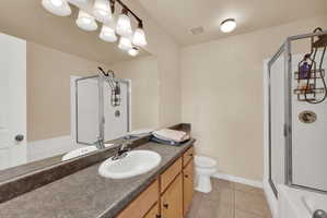 Bathroom featuring a stall shower, vanity, light tile patterned floors, and a tub to relax in