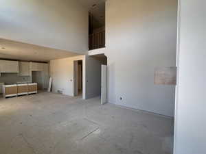 Two-story living area with an open-concept design, featuring a partial kitchen with white upper and lower cabinetry