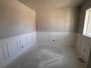 Interior room featuring paneled wainscoting, light gray wall paint, and a textured ceiling