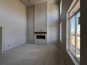 Two-story room featuring a floor-to-ceiling fireplace with a wood mantle, tall windows, and a high ceiling