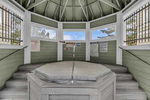 Wooden terrace featuring a gazebo and a hot tub