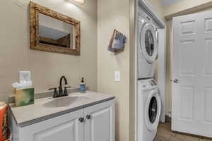 Laundry area with stacked washing machine and dryer and light tile patterned flooring
