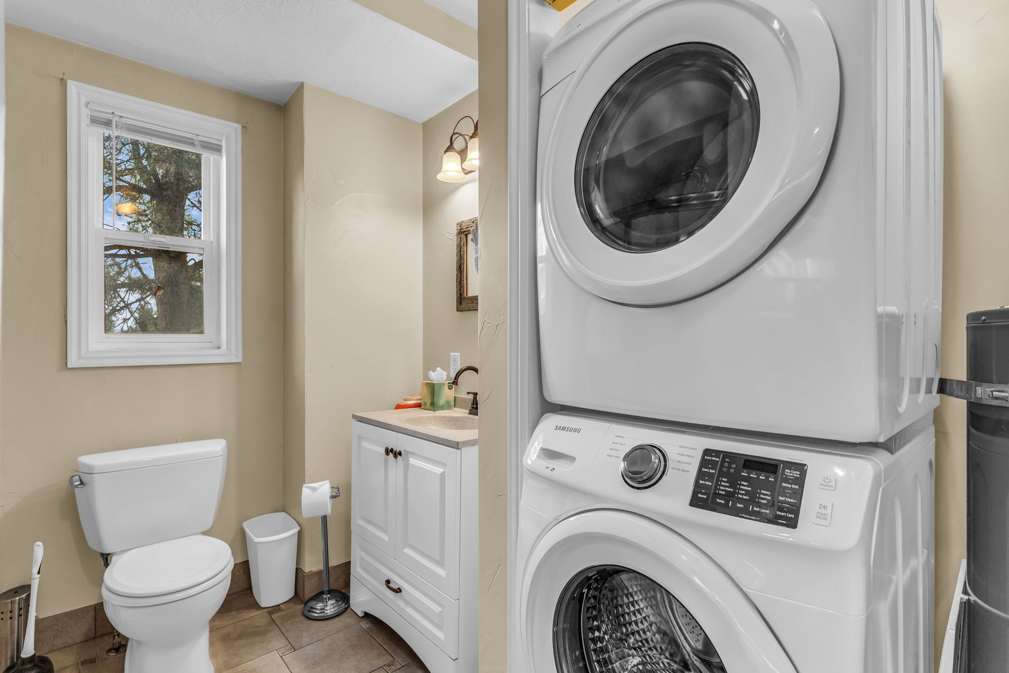 Laundry area with stacked washer and dryer and light tile patterned floors