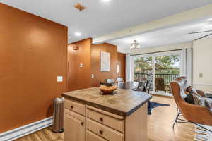 Kitchen with a baseboard radiator, tile countertops, light wood-style floors, beam ceiling, and light wood finish cabinets