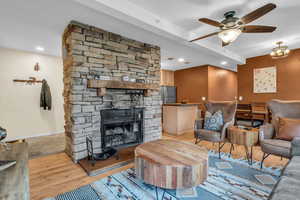 Living room featuring light wood-style floors, a fireplace, a ceiling fan, and recessed lighting