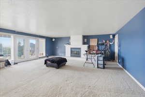 Carpeted living room with french doors, a glass covered fireplace, and a textured ceiling