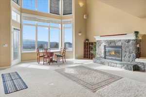 Living room featuring a fireplace, carpet flooring, a mountain view, and a high ceiling