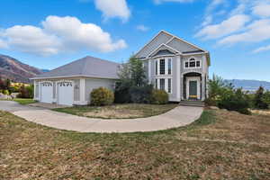 View of front of house with a mountain view, a front yard, a garage, driveway, and a shingled roof