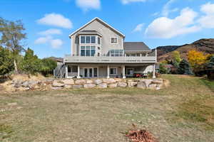 Rear view of house with a deck, a yard, and french doors