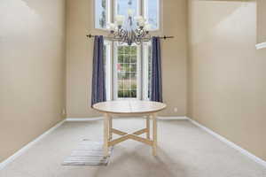 Dining area with light carpet, a high ceiling, and hanging lights
