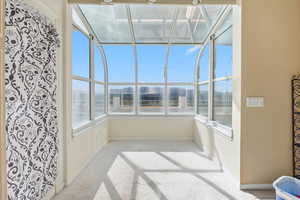 Unfurnished sunroom with healthy amount of natural light and carpet flooring