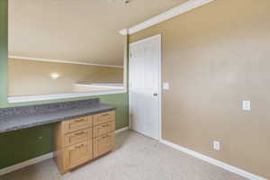 Office area featuring ornamental molding, light carpet, and built in study area