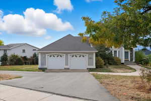 View of front of house featuring roof with shingles, a garage, driveway, and a front lawn