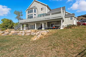 Rear view of property with a deck, french doors, a lawn, stucco siding, and a patio
