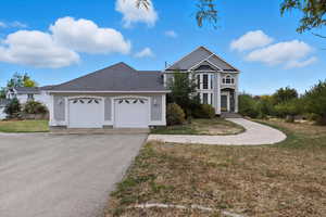 Traditional home with a shingled roof, a front lawn, driveway, and an attached garage