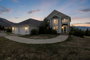 View of front of property featuring a mountain view, an attached garage, a yard, concrete driveway, and stucco siding