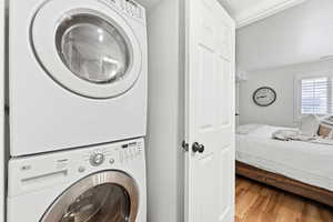 Laundry area featuring stacked washer and clothes dryer and light wood finished floors