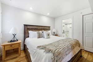 Bedroom featuring light wood-style flooring, ensuite bathroom, and recessed lighting