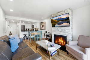 Living area with light wood-type flooring, a stone fireplace, and recessed lighting