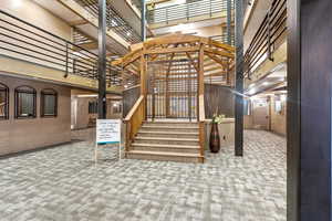 Stairs with a high ceiling, carpet floors, and brick wall