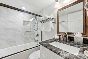 Full bathroom featuring vanity and shower / bath combination with glass door