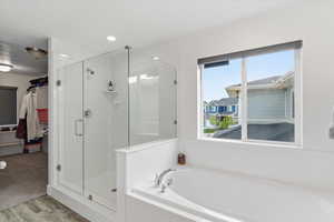 Bathroom with a stall shower, light wood finished floors, a bath, and recessed lighting