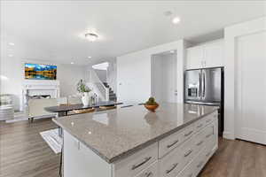 Kitchen with white cabinets, light stone counters, a center island, dark wood finished floors, and open floor plan