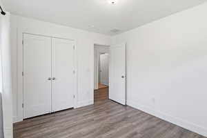 Unfurnished bedroom with dark wood-type flooring, a closet, and a textured ceiling