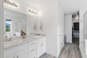 Bathroom featuring double vanity, light wood finished floors, and a stall shower